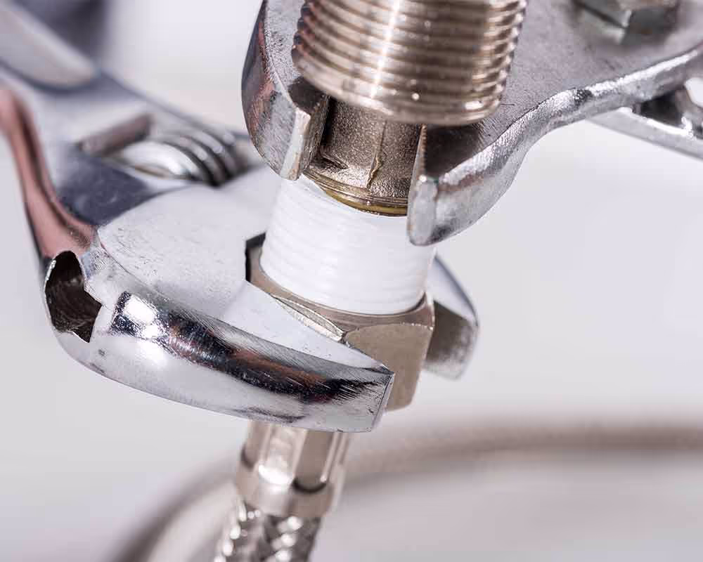 Plumber repairing pipe under kitchen sink with wrench